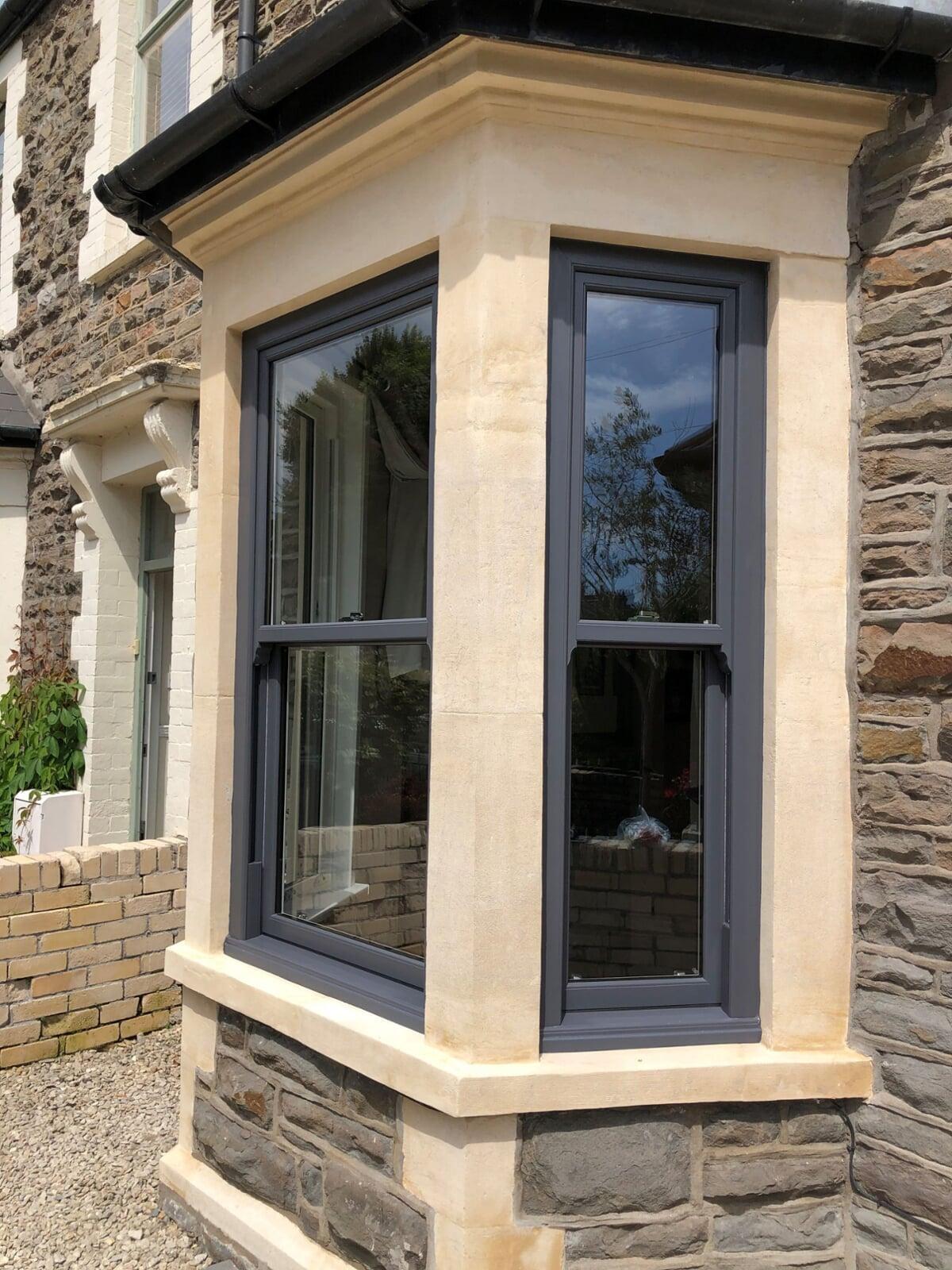 anthracite grey PVC sliding sash windows installed in traditional bay window