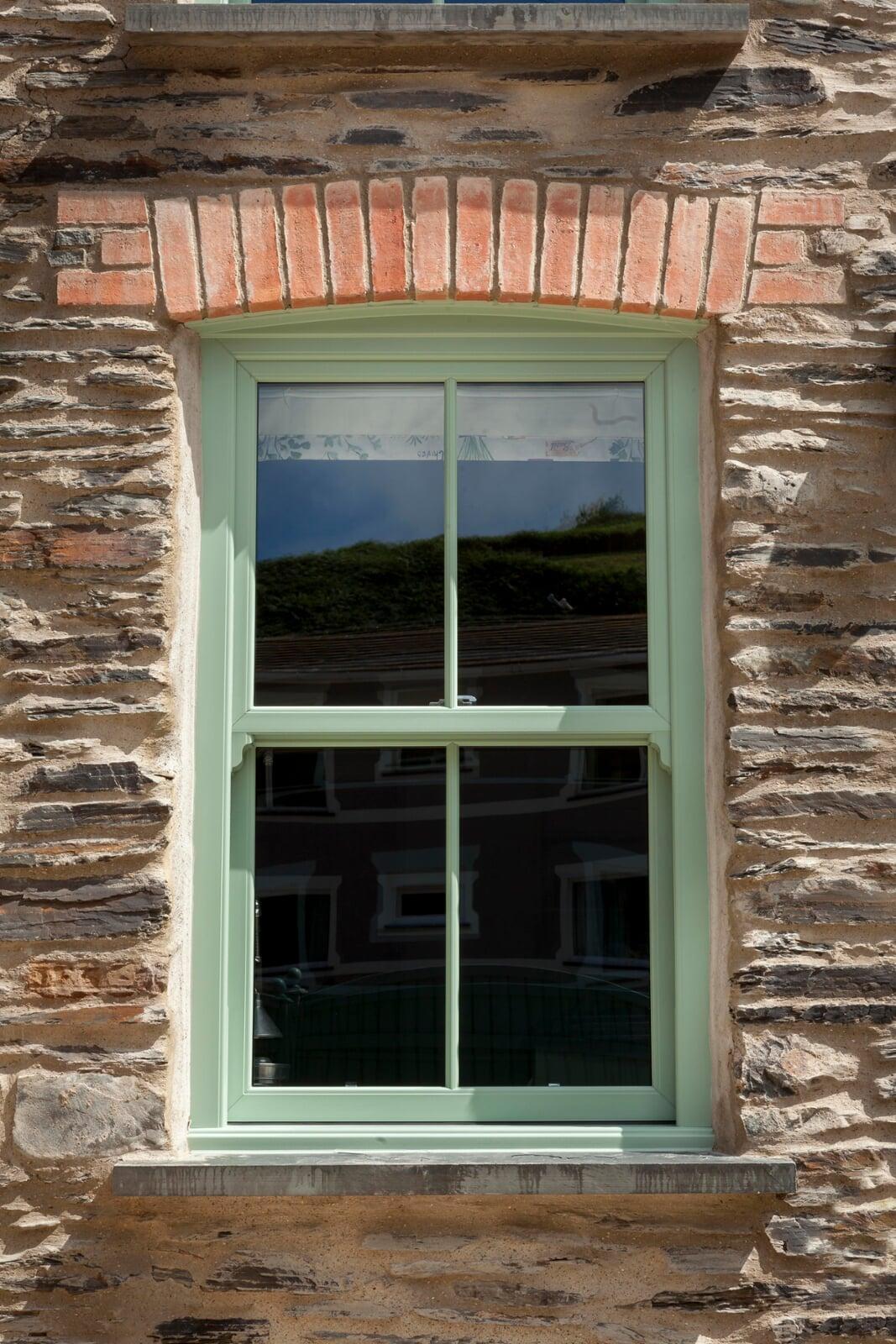 Chartwell green PVC sash window installed in traditional stone cottage