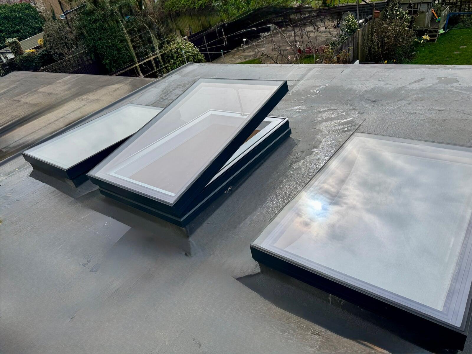 Trio  of contemporary flat rooflights on a flat roof one of the rooflights is open for ventilation. Installed in tooting SW17