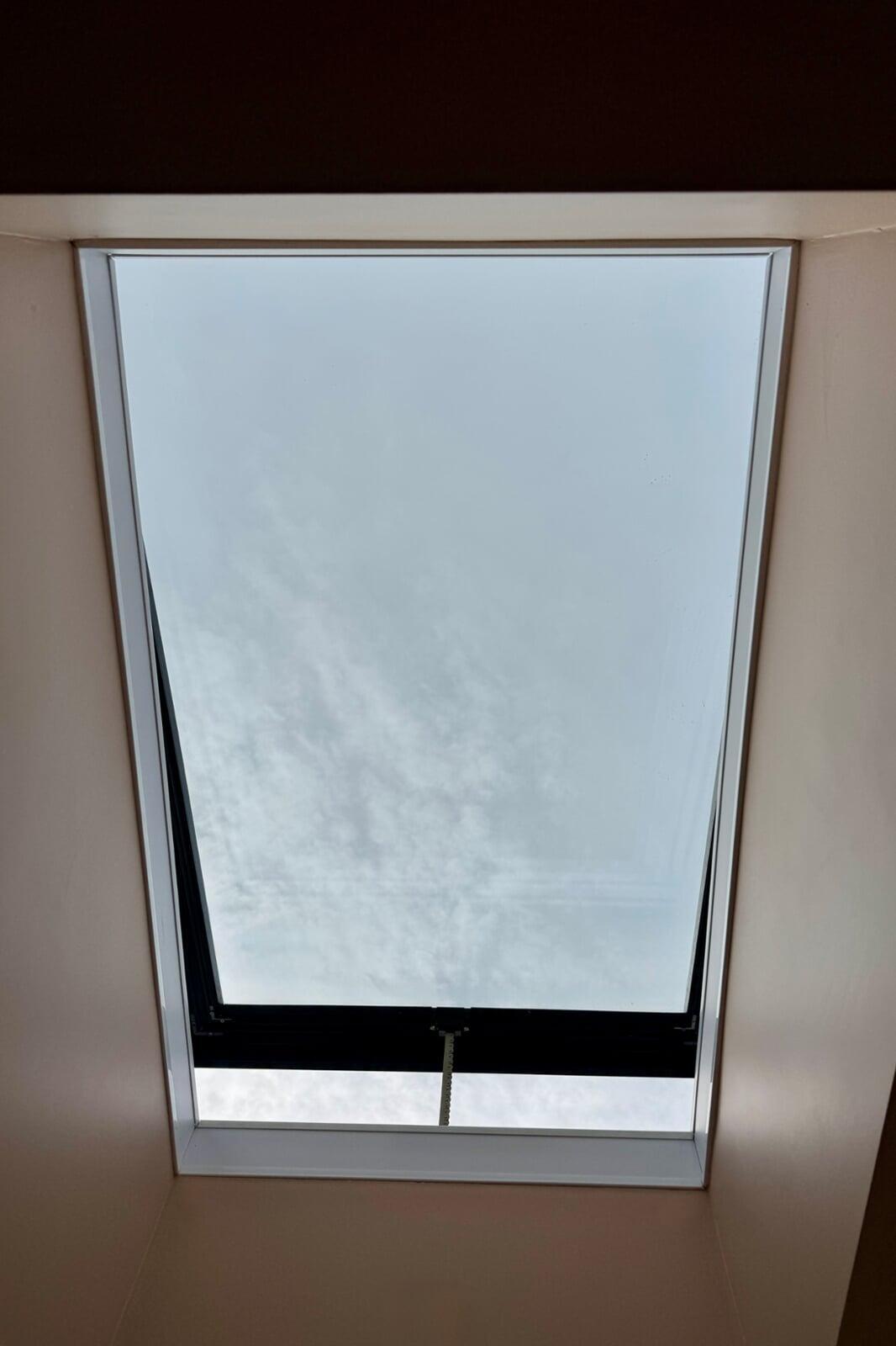 Opening rooflight window viewed from inside with sky visible above