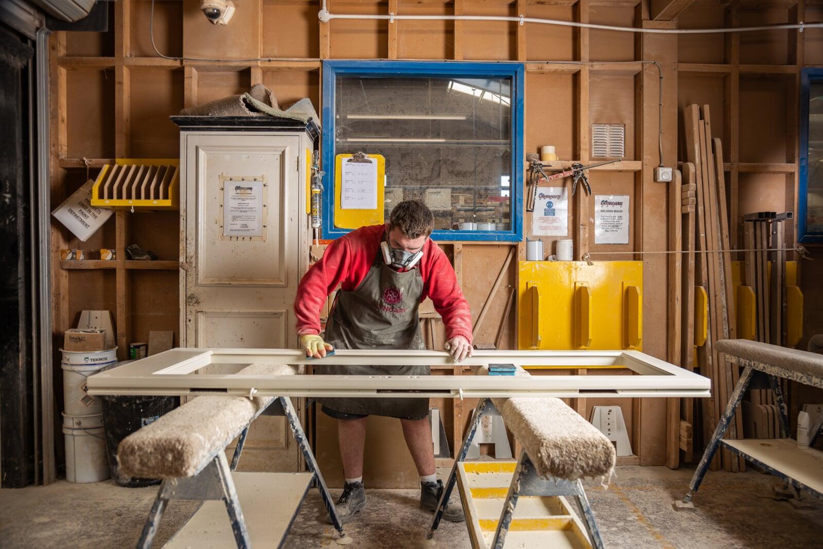 Joiner crafting timber entrance door using traditional woodworking techniques