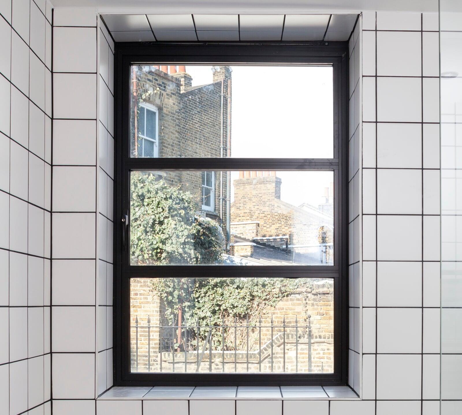 Slim-profile steel-look aluminium window in tiled interior setting