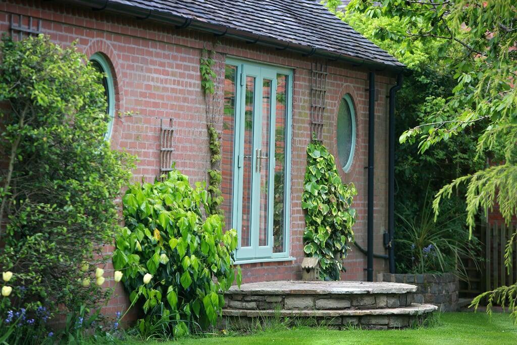 Glazed PVC French doors installed on a traditional brick garden room