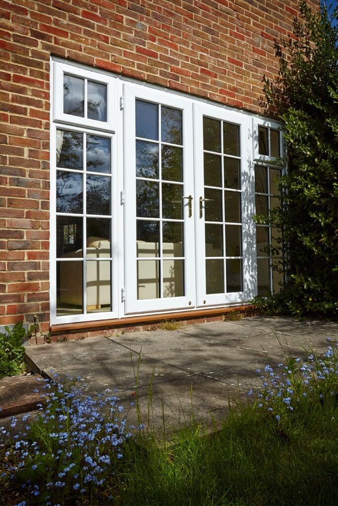 White PVC French doors with Georgian bars opening onto a brick patio