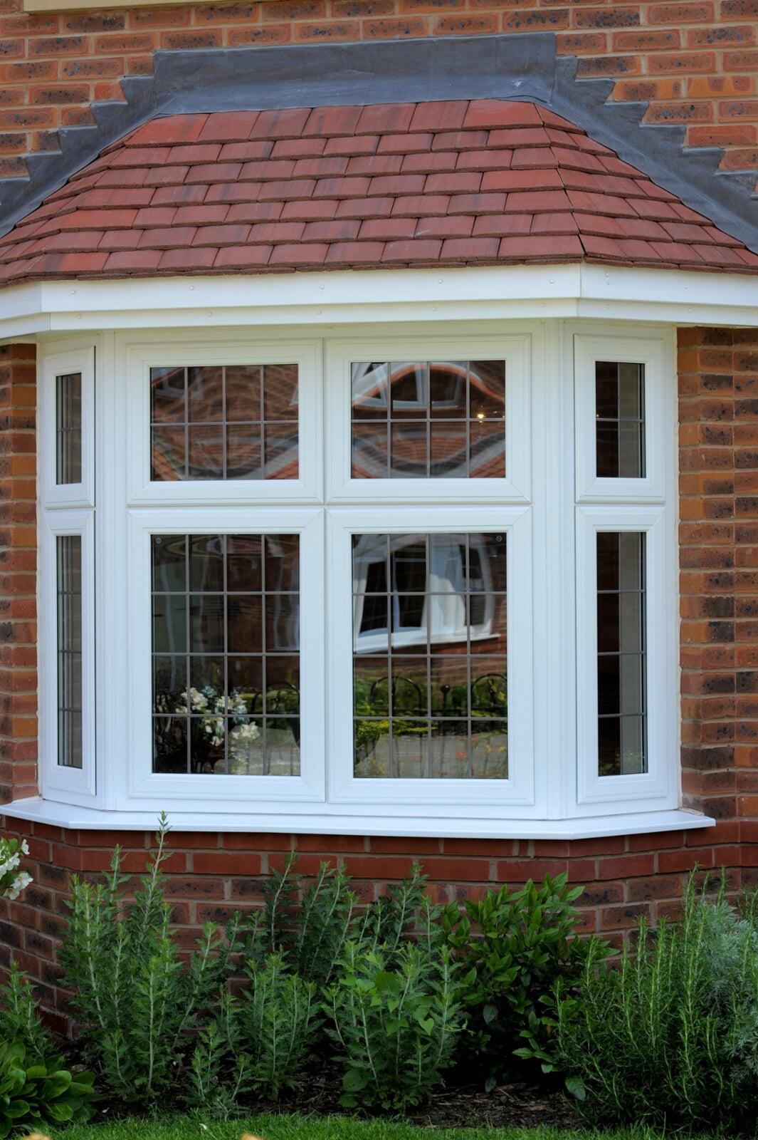 White stormproof PVC bay window installation on a traditional brick house