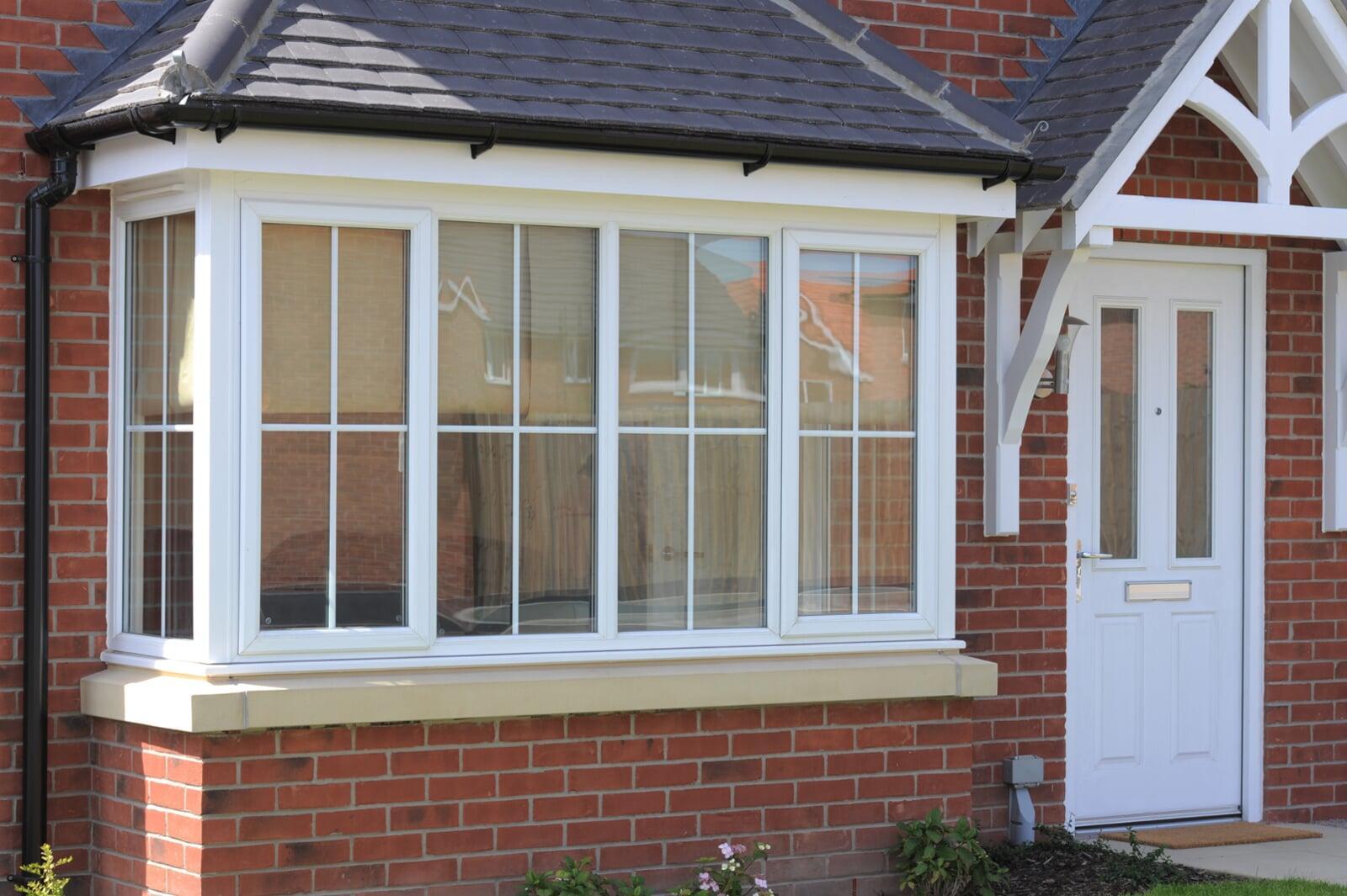 Stormproof PVC bay window installation on a brick home with white frames