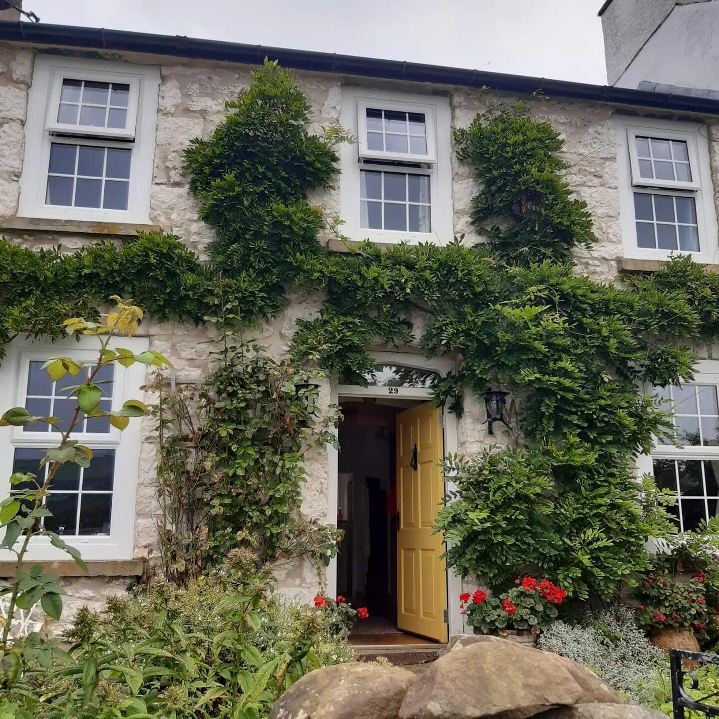 Traditional cottage with white PVC stormproof casement windows and climbing plants