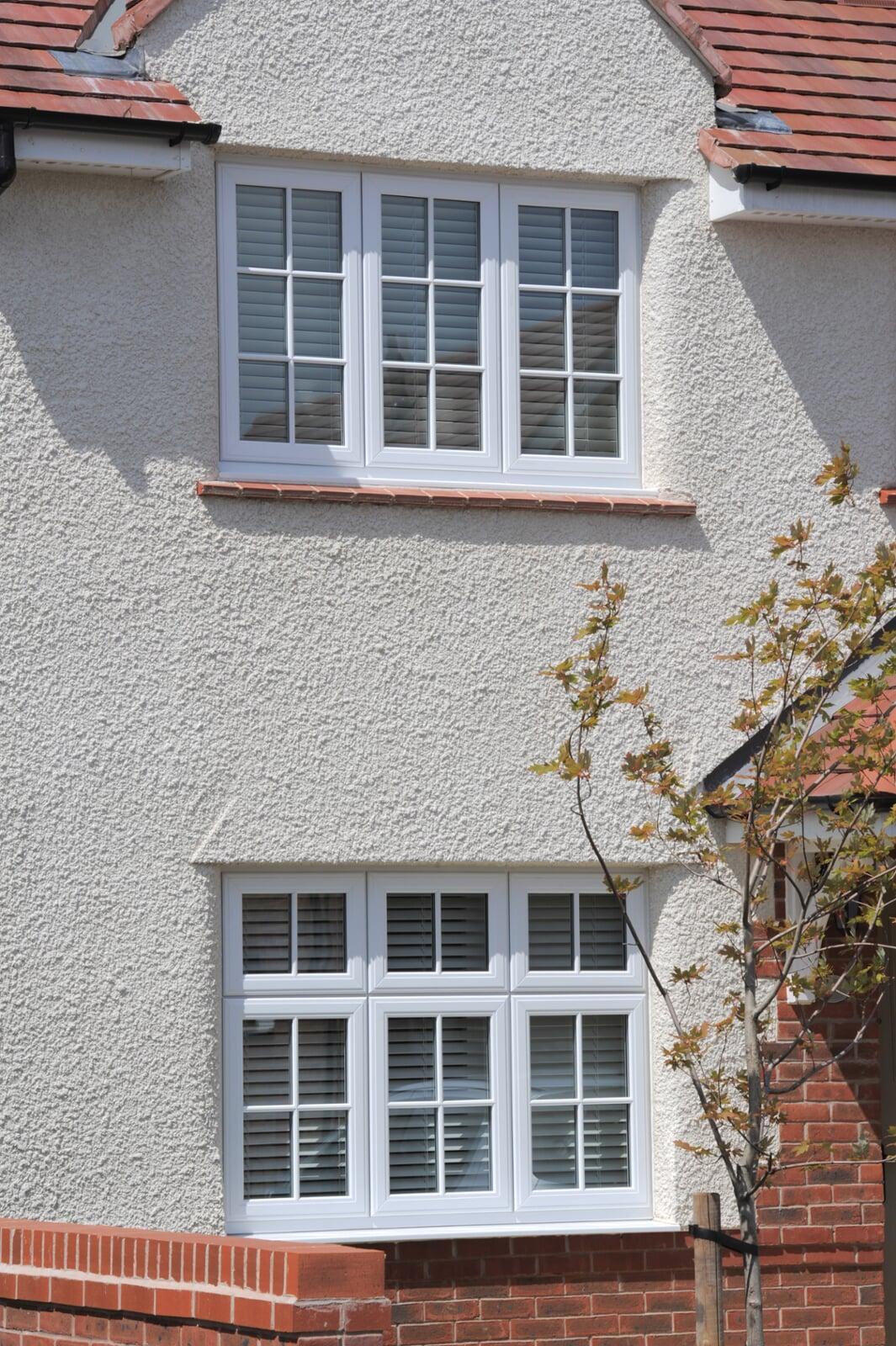 White PVC stormproof casement windows installed on a rendered house exterior